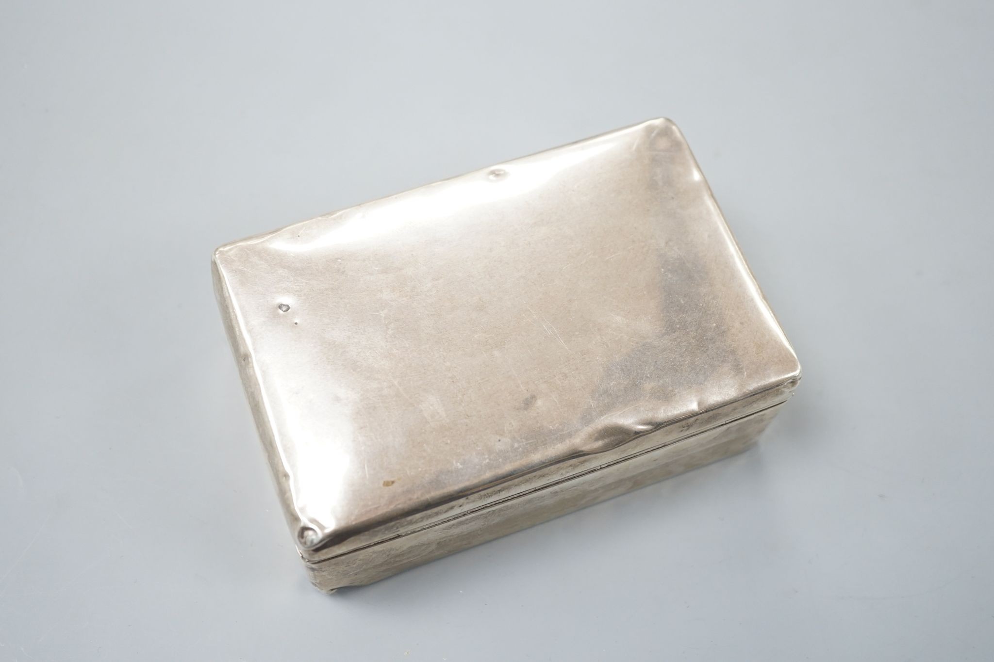 A silver mounted cigarette box, two silver vestas and a silver matchbox sleeve.